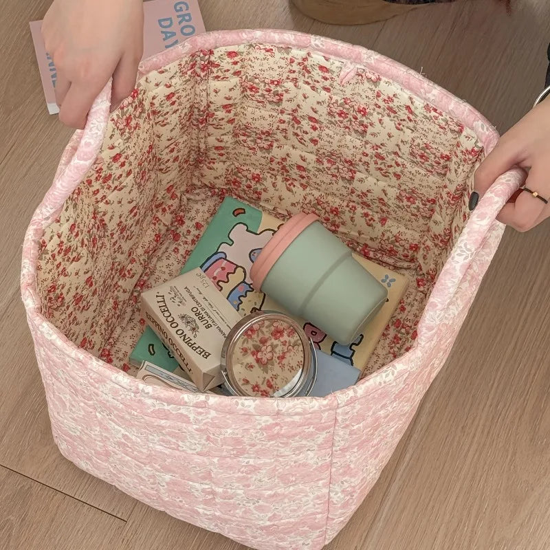 Floral-patterned fabric basket with stationery items on a wooden surface