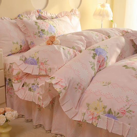 Floral bedding set with ruffles on a bed in a softly lit room.