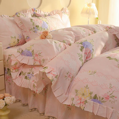 Floral bedding set with ruffles on a bed in a softly lit room.