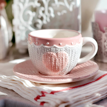 Pink and white ceramic cup and saucer set on a decorative love heart 