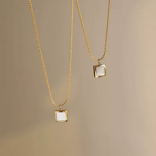 Two square-shaped amber pendant necklaces on gold chains, displayed against a neutral background.