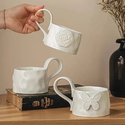 Three white ceramic mugs with embossed designs 