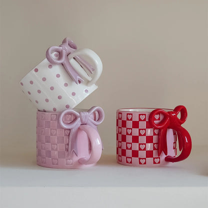 Three decorative mugs with bow designs 