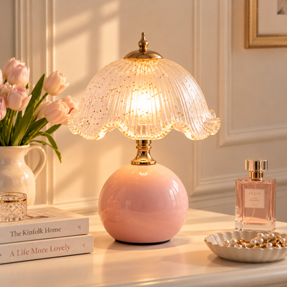 Vintage inspired pleated glass table lamp with a scalloped shade, gold tone detailing and rounded pink base, styled as elegant bedside lighting for a cosy bedroom.